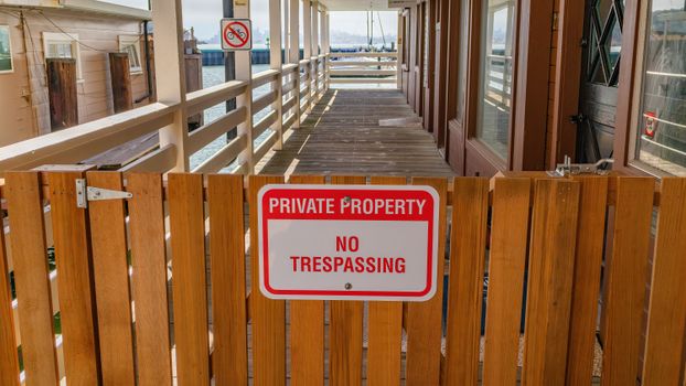 Wooden gate with a private property no trespassing sign in an outdoor setting.